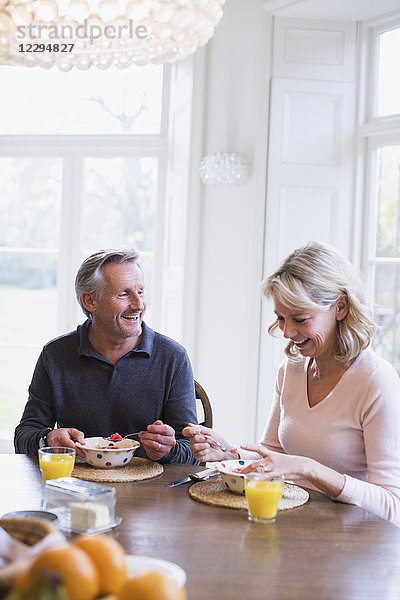 Lächelndes reifes Paar beim Frühstück am Esstisch