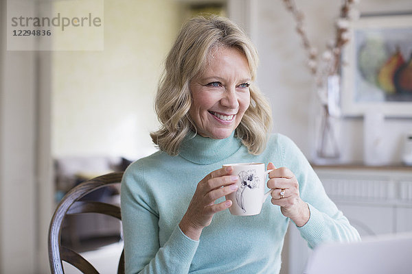 Lächelnde reife Frau trinkt Kaffee