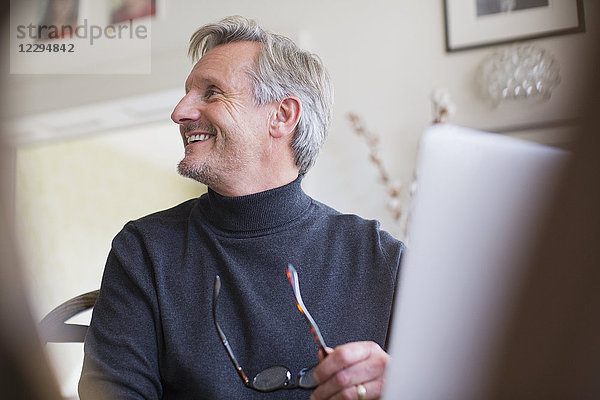 Lächelnder reifer männlicher Freiberufler arbeitet am Laptop