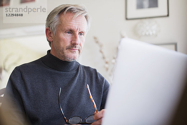 Fokussierter reifer männlicher Freiberufler  der zu Hause am Laptop arbeitet