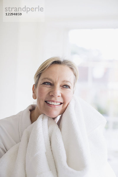 Lächelnde reife Frau trocknet Gesicht mit Handtuch