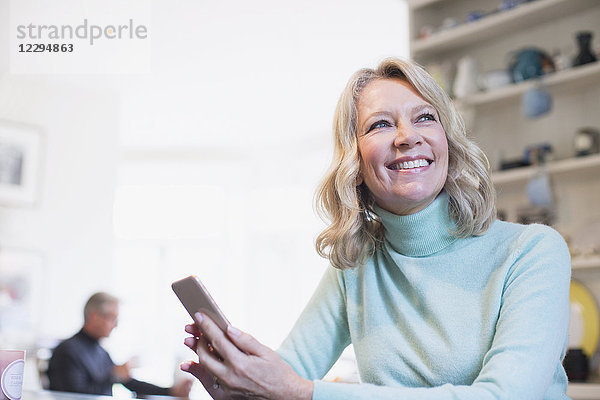 Lächelnde  selbstbewusste reife Frau  die ein Smartphone benutzt