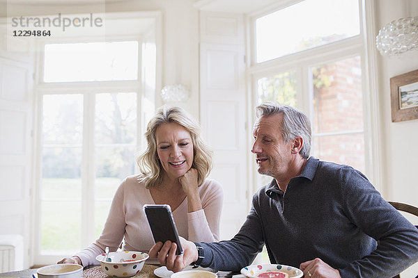 Älteres Paar benutzt Smartphone am Frühstückstisch