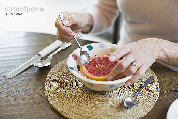 Frau isst Grapefruit mit Löffel