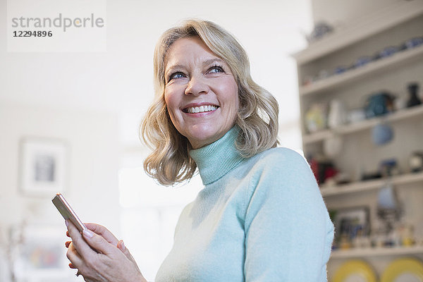 Porträt einer lächelnden  selbstbewussten reifen Frau  die eine SMS mit einem Smartphone schreibt