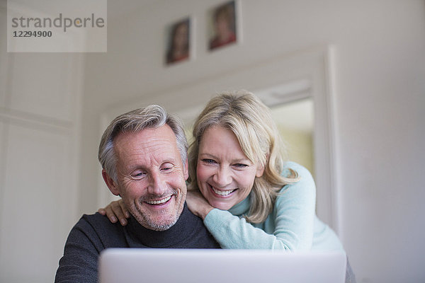 Lächelndes  glückliches reifes Paar  das einen Laptop benutzt