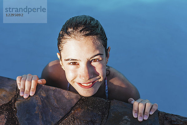Hochwinkel-Porträt eines nass lächelnden Mädchens am Pool