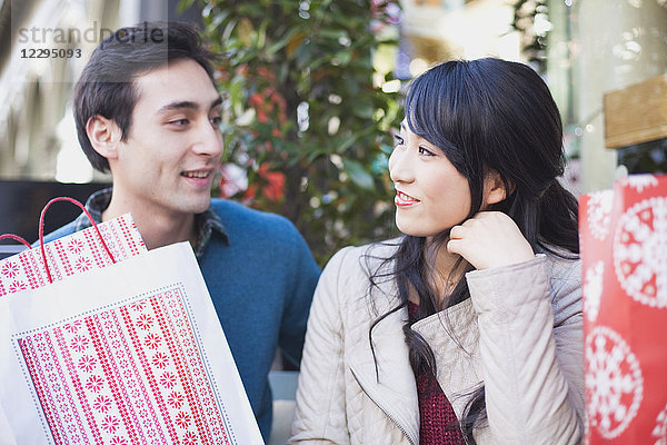 Liebevolles junges Paar mit Einkaufstaschen  die sich im Freien anschauen.
