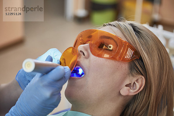Abgeschnittenes Bild des Zahnarztes  der der Patientin eine Füllung gibt.