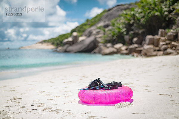 Tauchflossen mit Tauchermaske und aufblasbarem Ring am Strand gegen bewölkten Himmel  Seychellen