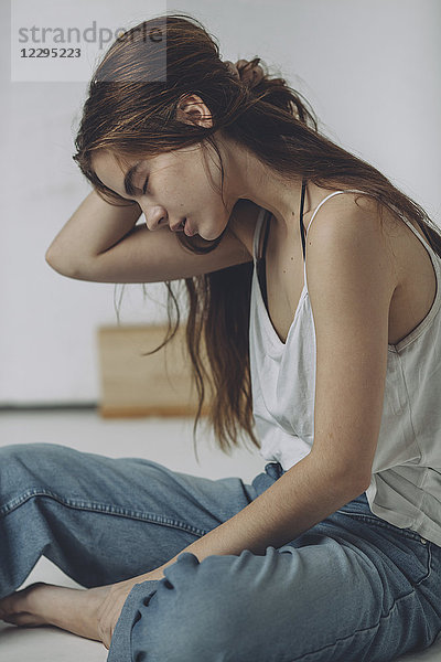 Volle Länge des Teenagermädchens auf dem Boden sitzend