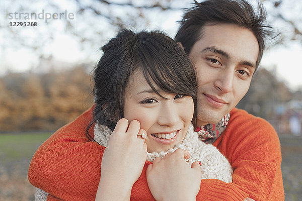 Lächelndes junges Paar  das sich im Winter im Park umarmt.