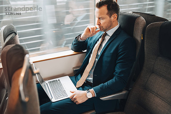 High angle view of businessman using laptop while traveling in train