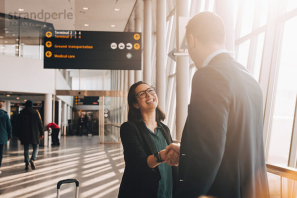 Smiling businesswoman shaking hand with businessman in airport terminal