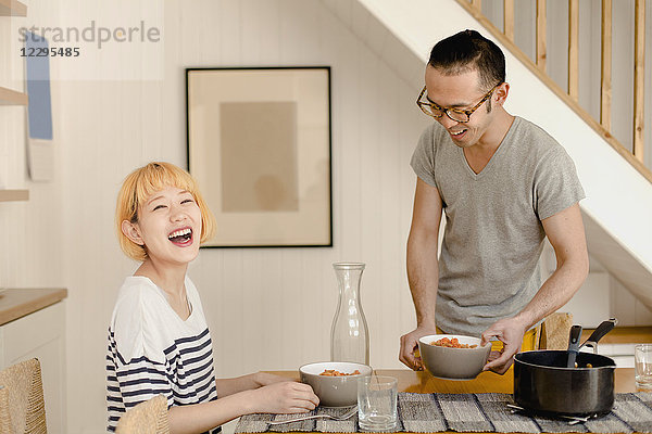 Glückliches junges Paar genießt das Essen auf dem Esstisch zu Hause