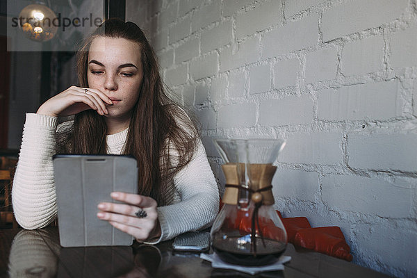 Junge Frau mit digitalem Tablett im Café