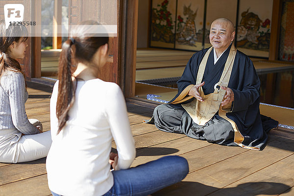 Japanischer Priester predigt zu Frauen in einem Tempel