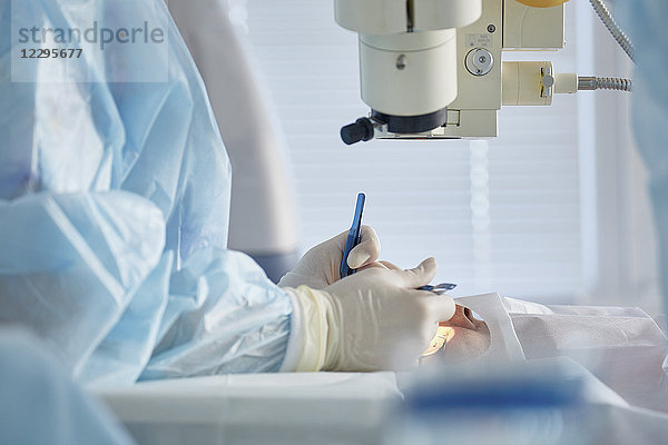 Mittelteil des Chirurgen  der eine Augenoperation am Patienten im Operationssaal durchführt.