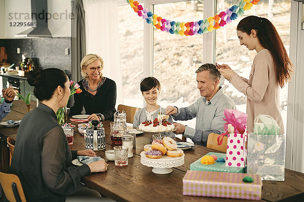 Multi-generation family enjoying birthday cake at table during party
