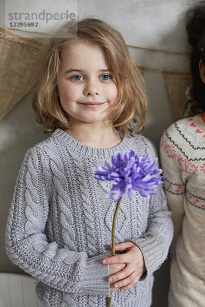 Porträt eines Mädchens mit violetter Blume  das mit einem Freund an der Wand steht.
