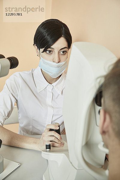 Augenoptiker bei der Untersuchung des Patientenauges im Krankenhaus