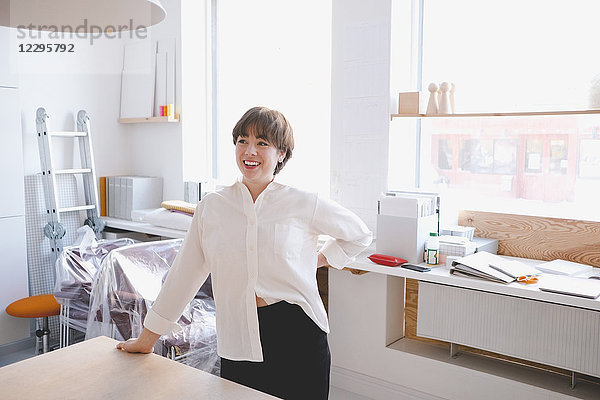 Smiling female design professional standing at desk in workshop