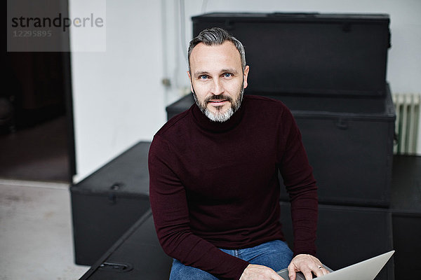 Portrait of confident businessman using laptop while sitting at office