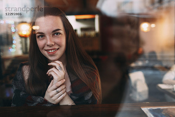 Lächelnd schöne junge Frau durch das Caféfenster gesehen