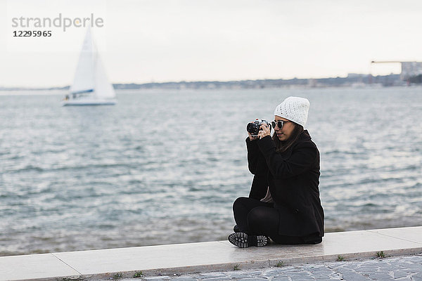 Volle Länge der Frau auf der Promenade beim Fotografieren am Wasser  Lissabon  Portugal