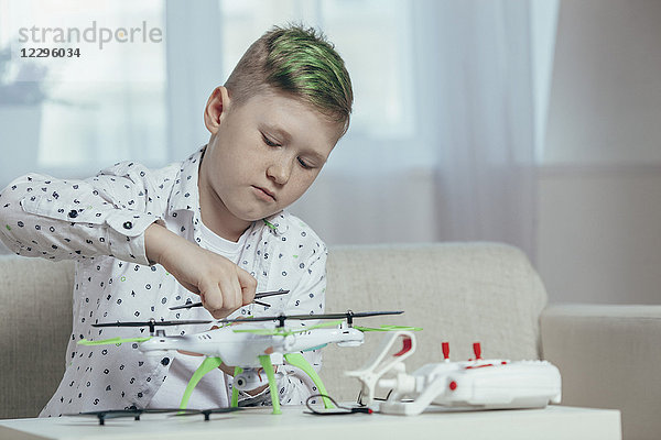 Souveräner Junge  der zu Hause auf dem Couchtisch sitzt und die Drohne anpasst