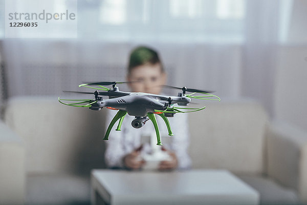 Junge fliegende Drohne im Wohnzimmer zu Hause