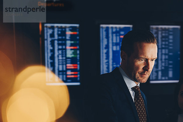 Confident businessman looking away while standing at airport