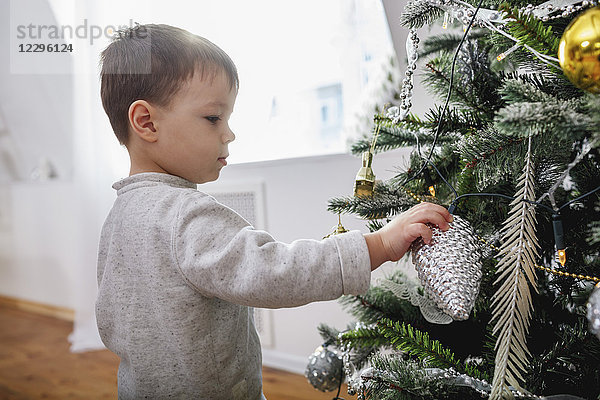 Seitenansicht des Jungen am Weihnachtsbaum zu Hause