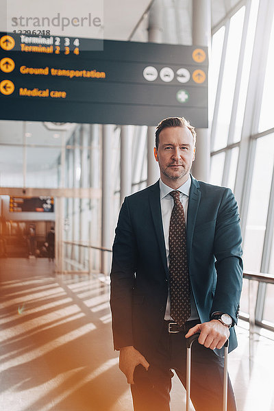 Portrait of confident mature businessman standing in airport terminal