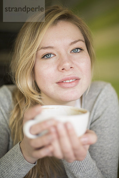 Porträt einer jungen Frau mit Kaffeetasse zu Hause