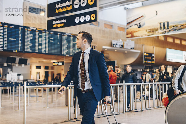 Mature businessman with luggage walking in airport terminal