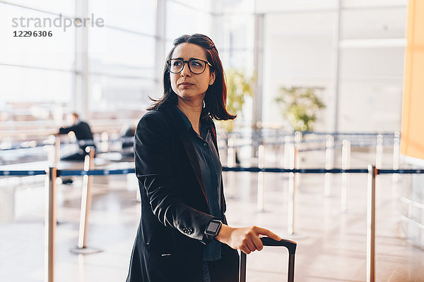 Mid adult businesswoman looking away in airport terminal