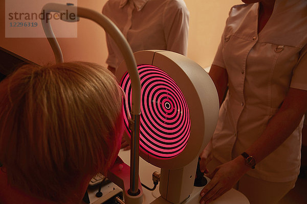 Krankenschwestern untersuchen Patienten mit Hornhauttopographen im Krankenhaus