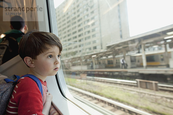 Neugieriger Junge  der durch ein Glasfenster schaut  während er im Zug fährt