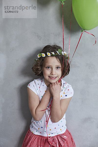 Porträt des lächelnden Mädchens mit Ballon an grauer Wand stehend