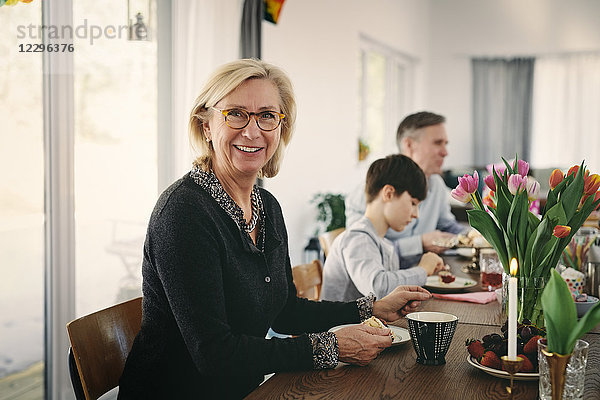 Portrait of smiling grandmother sitting with family at table during party
