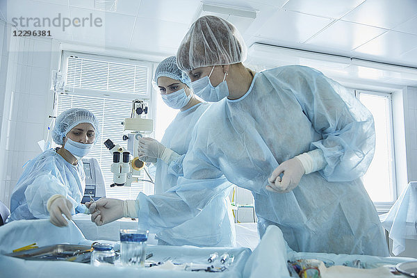 Chirurgin  die während der Operation im Krankenhaus medizinische Geräte an den Arzt weitergibt.