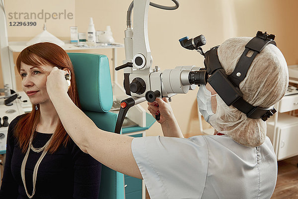 Arzt untersucht das Ohr der Patientin bei der Benutzung von Geräten im Krankenhaus