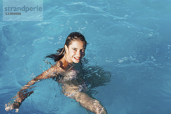 Hochwinkel-Porträt des lächelnden Mädchens beim Schwimmen im Pool