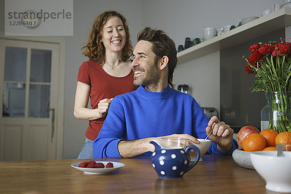 Fröhliches mittleres erwachsenes Paar bei Tisch mit Frühstück im Zimmer