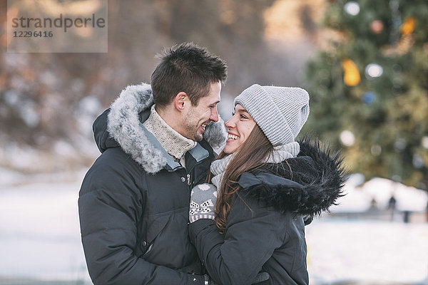 Lächelndes Paar in warmer Kleidung im Freien stehend