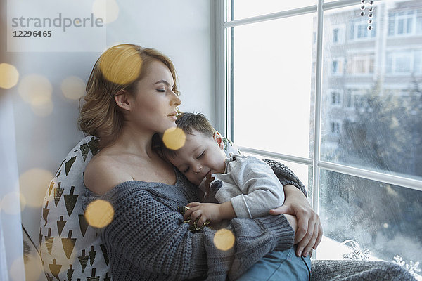 Junge Frau entspannt mit Sohn am Fenster zu Hause