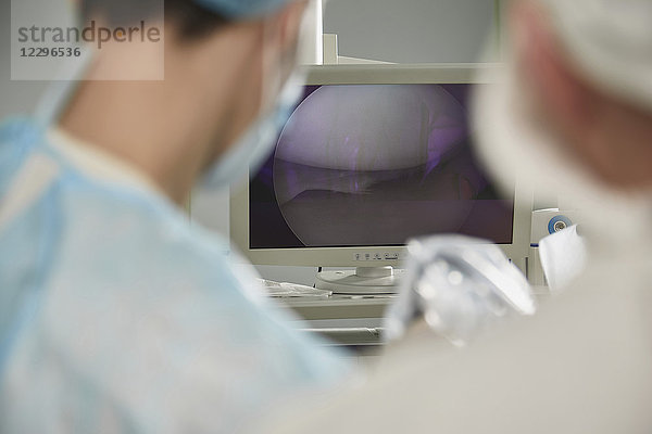 Männlicher Arzt beim Betrachten von Überwachungsgeräten im Operationssaal