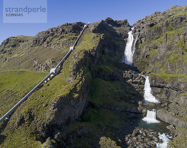 Blick auf den Wasserfall durch eine Wasserleitung am Berg  Island
