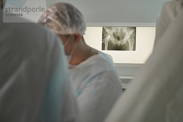 Chirurgen im Operationssaal mit medizinischem Röntgenbild am Bildschirm